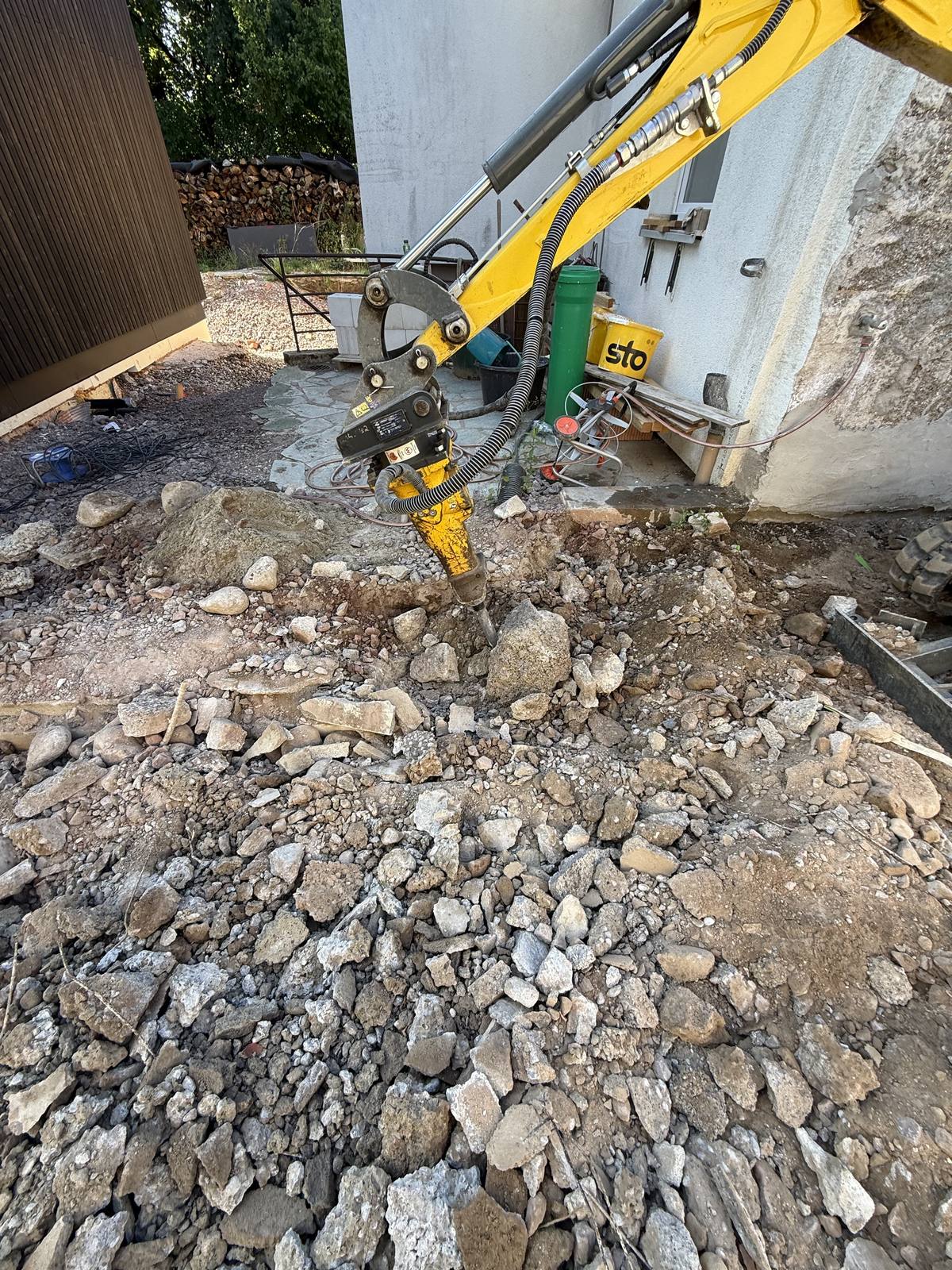 Hydraulikhammer am Bagger bricht Fundament und Steinboden auf